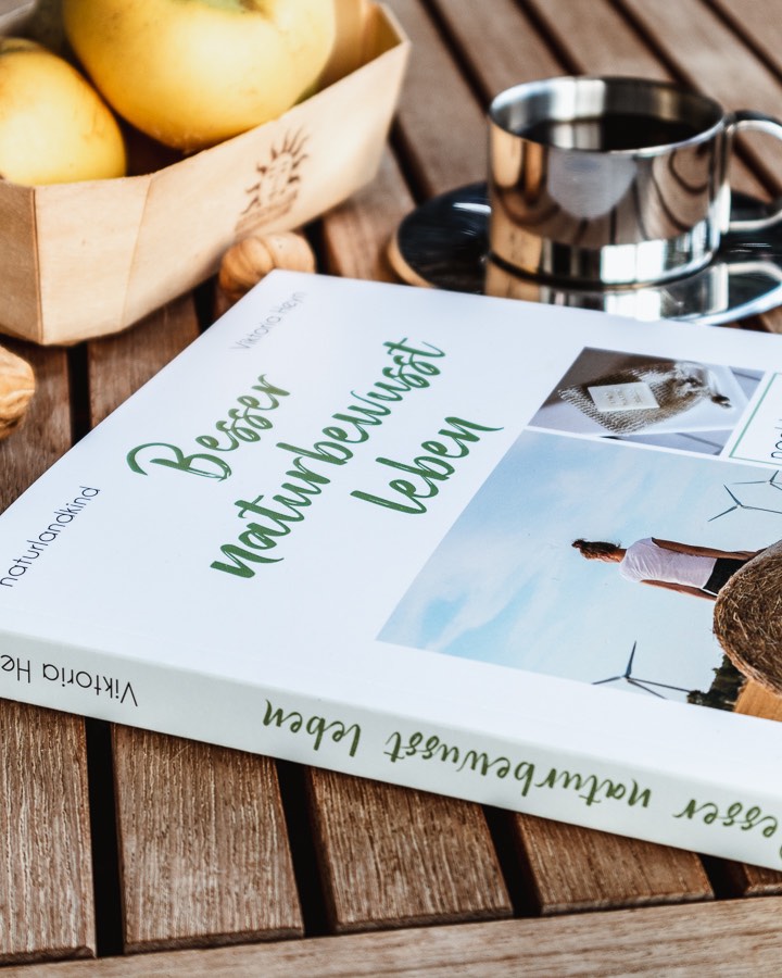 Das Buch "Besser naturbewusst leben" liegt neben einer Tasse Kaffee auf einem Tisch