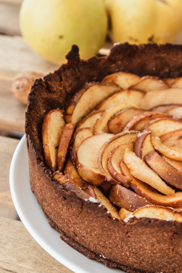 Quittenkuchen in einer Springform: Im Hintergrund liegen zwei Quitten und eine Walnuss